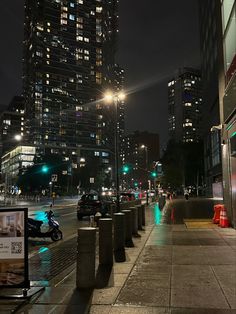 a city street at night with tall buildings in the background