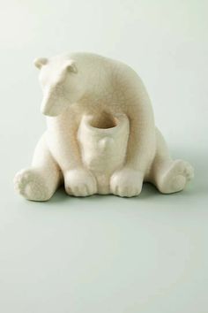 a white ceramic polar bear holding a baby cub in it's mouth, on a gray background