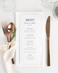 a table setting with utensils, silverware and menu cards on it's side