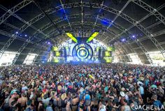 a large group of people standing in front of an outdoor concert stage with lights on