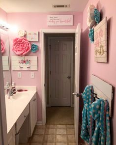 a bathroom decorated in pink and blue with towels hanging on the wall, along with two sinks