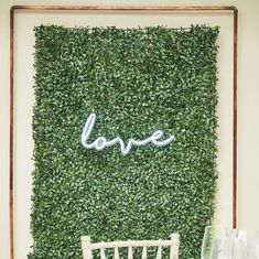 there is a green wall with the word love on it and two chairs in front of it