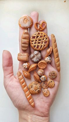 a person's hand holding various types of breads and pastries