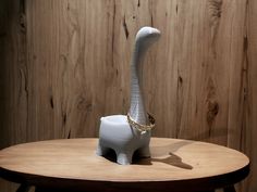 a white elephant shaped vase sitting on top of a wooden table next to a wall