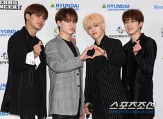 three young men standing next to each other on a red carpet