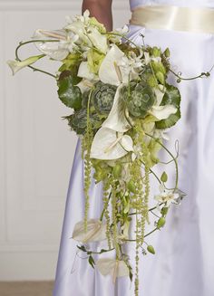 a bride holding a bouquet of flowers and greenery