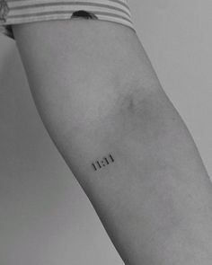 a person with a small tattoo on their arm that reads 11 11 in black ink