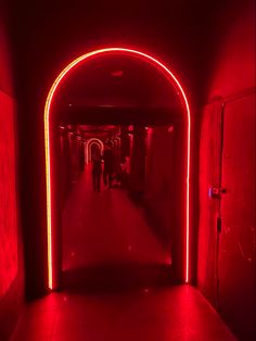 a long hallway with red lights and people walking down it