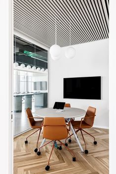 a table with four chairs and a laptop on it in front of a flat screen tv