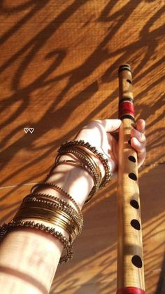 a close up of a person's hand holding a long wooden pole with bracelets on it