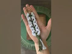 a person's hand holding some white and green beads