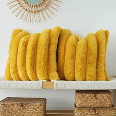 four yellow pillows sitting on top of a white shelf next to two wicker baskets