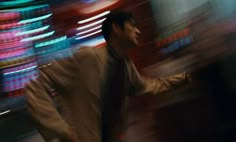 a blurry image of a man walking down the street in front of neon signs