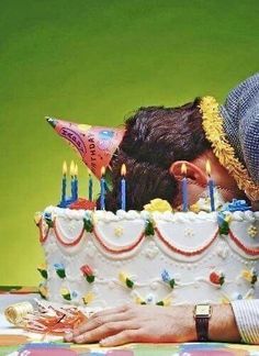 a couple kissing in front of a birthday cake with candles on it and two people leaning over the cake