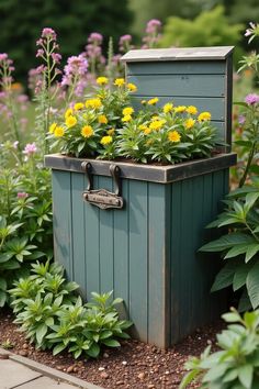 a wooden box with flowers growing out of it in the middle of a flower garden