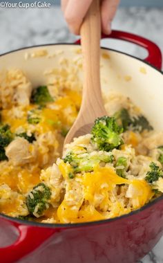 a red pot filled with chicken and broccoli on top of a marble counter