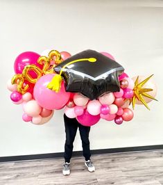 a person holding balloons and a graduation cap