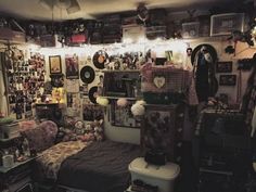 a room filled with lots of clutter and stuffed animals on the wall next to a bed