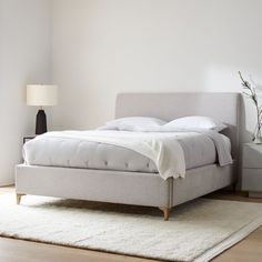 a bed sitting on top of a wooden floor next to a white wall