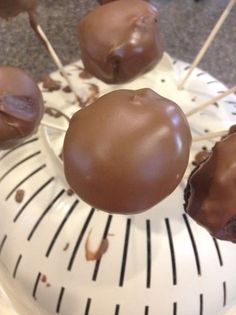 several chocolate covered donuts sitting on top of a white plate with toothpicks sticking out of them