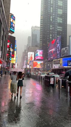 two people walking down the street in the rain with umbrellas over their heads and buildings behind them