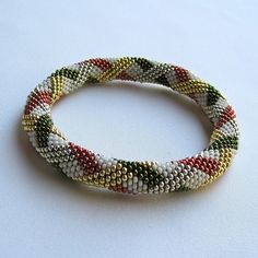 a close up of a beaded bracelet on a white surface with an object in the background