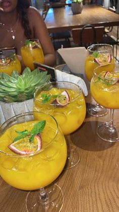 three glasses filled with drinks sitting on top of a wooden table