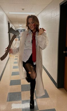 a woman dressed as a zombie holding a hammer and wearing a red tie, white coat and black boots