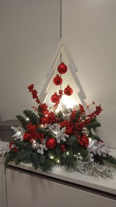 a christmas tree with ornaments and lights on it's mantle in front of a white wall