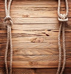 rope on wooden planks with knots hanging from the top and below it, against a rustic wood background