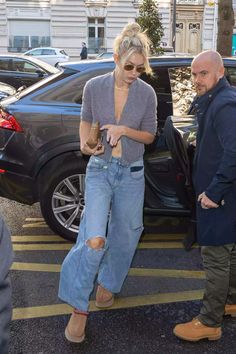 a woman in ripped jeans is standing next to a man