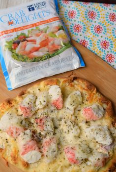 a bag of crab delights next to a pizza on a cutting board with a packet of shrimp