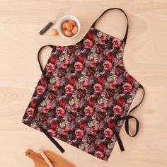 an apron with flowers on it next to wooden spoons, eggs and utensils