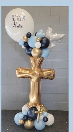 a gold cross with blue and white balloons