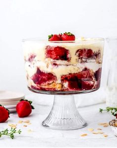 a layered dessert with strawberries and cream in the middle on a glass cake stand