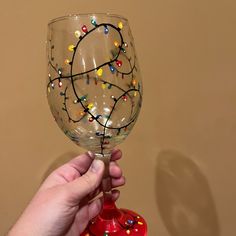 a hand holding a wine glass decorated with christmas lights