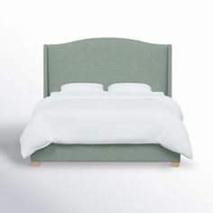 a bed with white sheets and green headboard