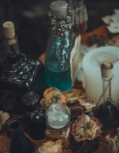 an assortment of candles and vases on a table with other items in the background