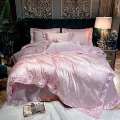 a bed with pink comforter and pillows on top of white fluffy carpeted floor