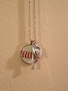 Round pendant with real baseball leather. Up to two numbers OR charms added at no charge. Silver tone necklace and pendant. 24 inch chain. (Add'l charms or changes may increase cost) I have these silver tone charms:        PLEASE READ *individual numbers-0-9. I also have 10, 11, 12, 14, 14, 18, 18, 21, 30, 40 and 50.  If you want any other double digit numbers I have to use two individual  numbers.  *baseball/softball cap *bat *glove/ball *I <3 baseball *Baseball Mom See second picture for choic Diy Baseball Jewelry, Baseball Mom Necklace, Sport Necklaces, Baseball Chain Necklaces, Softball Necklace, Baseball Gifts, Baseball Mom, Round Pendant, Leather Necklace