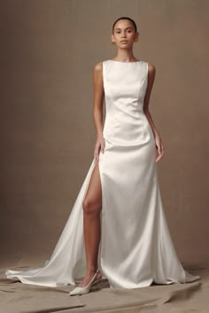 a woman wearing a white dress with a slit in the side and one leg up