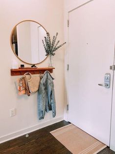 a mirror, coat rack and rug in a white room with wood flooring on the walls