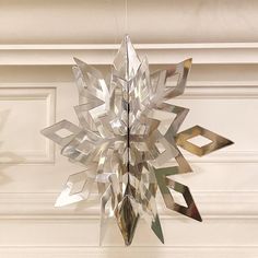 a metal snowflake hanging from the ceiling in front of a white wall and door