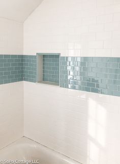 a bath tub sitting under a window in a bathroom next to a tiled wall and floor