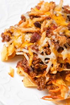 a white plate topped with cheesy hash browns and cheese covered nachos