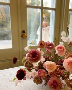 a vase filled with lots of flowers sitting on top of a table next to a window