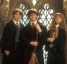 three harry potters standing in front of a stained glass window with broom and book