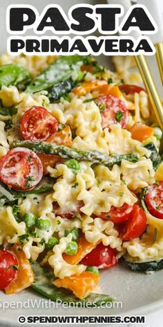 pasta prima primavera with tomatoes, asparagus and spinach on a white plate