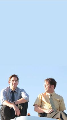 two men sitting on the roof of a car looking at something in the sky above them