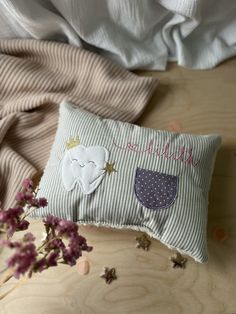 a pillow that has been placed on a table with some flowers in front of it